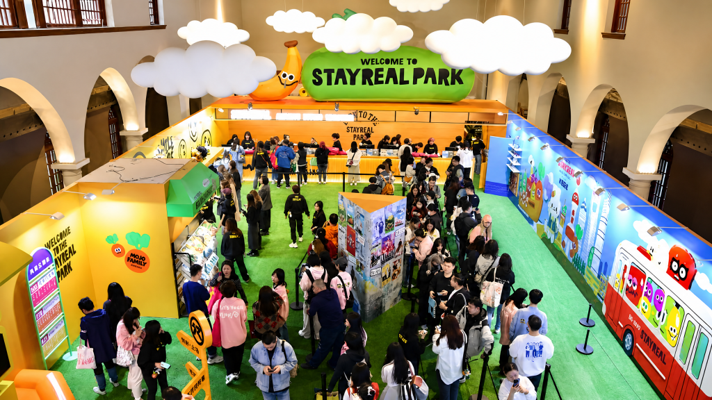 Custom trade show giveaway booth scene with anime-style acrylic keychains, button pins, photo cards, blind boxes and plush mascots